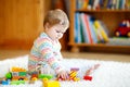 Adorable cute beautiful little baby girl playing with educational wooden toys at home or nursery. Toddler with colorful Royalty Free Stock Photo