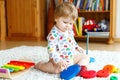 Adorable cute beautiful little baby girl playing with educational wooden toys at home or nursery. Toddler with colorful Royalty Free Stock Photo