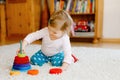 Adorable cute beautiful little baby girl playing with educational wooden toys at home or nursery. Toddler with colorful Royalty Free Stock Photo