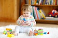 Adorable cute beautiful little baby girl playing with educational wooden toys at home or nursery. Toddler with colorful Royalty Free Stock Photo