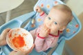 Adorable cute caucasian blond toddler boy eating tasty vegetable soup in chair at kithcen indoor. Mother feeding baby healthy food Royalty Free Stock Photo