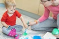 Adorable cute caucasian little blond toddler boy enjoy having fun finger painting with young beautiful mother at home Royalty Free Stock Photo