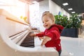 Adorable cute caucasian little toddler boy having fun playing big white piano in mall indoor. Funny happy small child enjoy Royalty Free Stock Photo