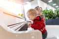 Adorable cute caucasian little toddler boy having fun playing big white piano in mall indoor. Funny happy small child enjoy Royalty Free Stock Photo