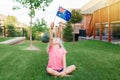 Adorable cute happy Caucasian girl holding Australian flag. Smiling child sitting on grass in park holding Australia flag. Kid Royalty Free Stock Photo