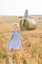Adorable cute little baby girl in nice striped dress walking in summer wheat field. Pretty young mother sitting on hay Royalty Free Stock Photo