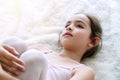 Little ballet girl brown long hair lying on white fur rug while looking at camera . Top view lovely kid lying down Royalty Free Stock Photo