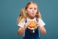 Adorable cute little girl in white shirt and jean jumpsuit with hamburger Royalty Free Stock Photo