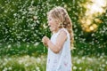 Adorable cute little preschool girl blowing on a dandelion flower on the nature in the summer. Happy healthy beautiful Royalty Free Stock Photo