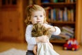 Adorable cute little toddler girl playing with doll. Happy healthy baby child having fun with role game, playing mother Royalty Free Stock Photo