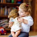 Adorable cute little toddler girl playing with doll. Happy healthy baby child having fun with role game, playing mother Royalty Free Stock Photo