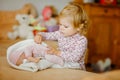 Adorable cute little toddler girl playing with doll. Happy healthy baby child having fun with role game, playing mother Royalty Free Stock Photo