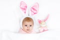 Adorable cute newborn baby girl in Easter bunny costume and ears. Lovely child playing with plush rabbit toy. Holiday Royalty Free Stock Photo