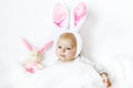 Adorable cute newborn baby girl in Easter bunny costume and ears. Lovely child playing with plush rabbit toy. Holiday Royalty Free Stock Photo