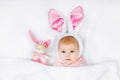 Adorable cute newborn baby girl in Easter bunny costume and ears. Lovely child playing with plush rabbit toy. Holiday Royalty Free Stock Photo