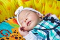 An adorable cute newborn baby girl wearing a white headband fast asleep on a play blanket Royalty Free Stock Photo