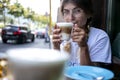 Cute pretty young woman drinks coffee milk foam Royalty Free Stock Photo