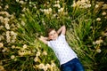 Adorable cute school boy laying on grass on a dandelion flower field the nature in the summer. Happy healthy beautiful Royalty Free Stock Photo
