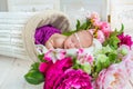 Adorable cute sweet sleeping baby girl in white basket with flowers on wooden floor