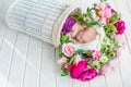 Adorable cute sweet sleeping baby girl in white basket with flowers on wooden floor Royalty Free Stock Photo