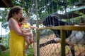 Adorable cute toddler girl with mother feeding goat on a kids farm. Beautiful baby child petting animals in the zoo Royalty Free Stock Photo