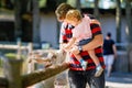 Adorable cute toddler girl and young father feeding little goats and sheeps on a kids farm. Beautiful baby child petting