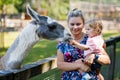 Adorable cute toddler girl and young mother feeding little goats and sheeps on kids farm. Beautiful baby child petting Royalty Free Stock Photo