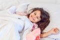 Adorable dark hair girl sleeping sweetly in the morning on wihte bed linens at home. Childrens dreams, comfort, rest and