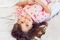 Adorable dark hair girl sleeping sweetly in the morning on wihte bed linens at home. Childrens dreams, comfort, rest and