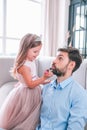 Adorable daughter in dress applying lipstick on daddy lips, spending time together at home