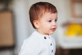 Adorable dreamy little boy toddler with blue eyes standing indoors Royalty Free Stock Photo