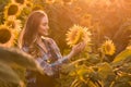 Adorable, energetic, female farmer examining sunflowers in the middle of a beautiful sunflower field, during a scenic sunrise Royalty Free Stock Photo