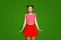 Adorable fancy young girl wear in red skirt and striped tshirt stand upright look at the camera isolated on red