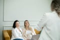 Female team discussing work ins in home office. Brunette and preggers lady sitting on sofa and listening to colleague. Royalty Free Stock Photo