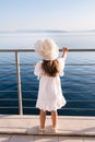 Adorable five year old girl in beautiful white dress and hat looking at the sea from height. Looking on sunset Royalty Free Stock Photo