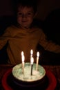 Adorable five year old kid celebrating his birthday and blowing candles on homemade baked cake, indoor. Birthday party