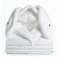 Adorable fluffy bunny bathrobe folded on a stack of pristine towels on white background Royalty Free Stock Photo