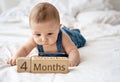 Adorable four month old baby boy in denim dungarees lying on white bed Royalty Free Stock Photo