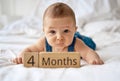 Adorable four month old baby boy in denim dungarees lying on white bed Royalty Free Stock Photo