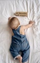 Adorable four month old baby boy in denim dungarees lying on white bed Royalty Free Stock Photo