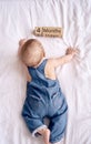 Adorable four month old baby boy in denim dungarees lying on white bed Royalty Free Stock Photo