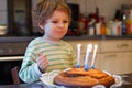 Adorable four year old boy celebrating his birthday and blowing Royalty Free Stock Photo