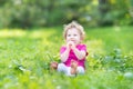 Adorable funny curly baby girl eating candy in sunny park