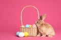 Adorable furry Easter bunny near wicker basket and dyed eggs Royalty Free Stock Photo