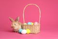 Adorable furry Easter bunny near wicker basket and dyed eggs Royalty Free Stock Photo