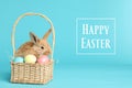 Adorable furry Easter bunny in wicker basket with dyed eggs on color background Royalty Free Stock Photo