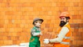 Adorable future architect over a brick background. Little cute son helping his father with building work. Happy team Royalty Free Stock Photo