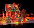 Adorable gingerbread family near big snow-covered homemade gingerbread house with Christmas lights