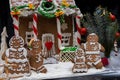 Adorable gingerbread family near snow-covered homemade gingerbread house on dark background