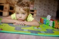 Adorable gingerish little boy laying on floor, playing with building cubes